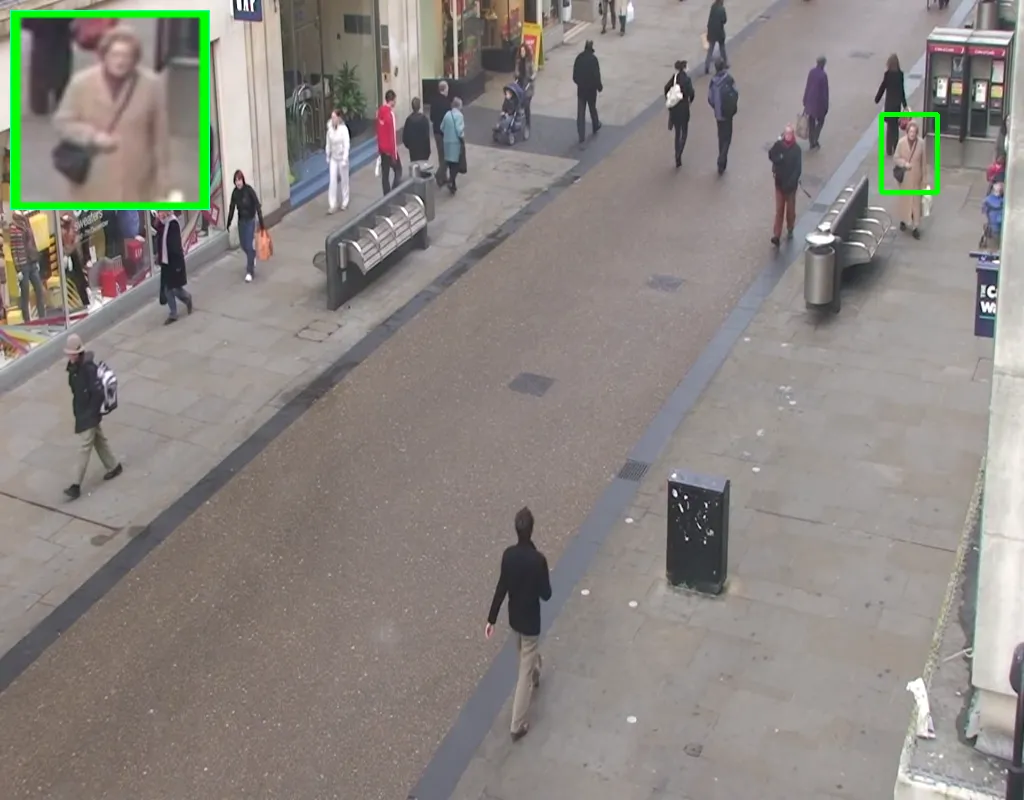 The tracked pedestrian now clearly resolved in the inset panel, with the green box following her along the right-hand pavement
